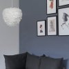 Miljöbild på EOS Evia, fjäderlampa, här vid en soffa framför en snygg fondvägg i trendriktigt blå färg med tavelvägg