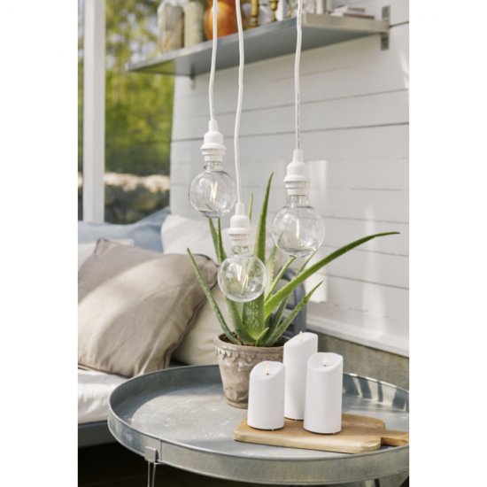 Vacker dekoration utomhus med tre vaxljus blockljus på en bricka med stenar och hängande belysning